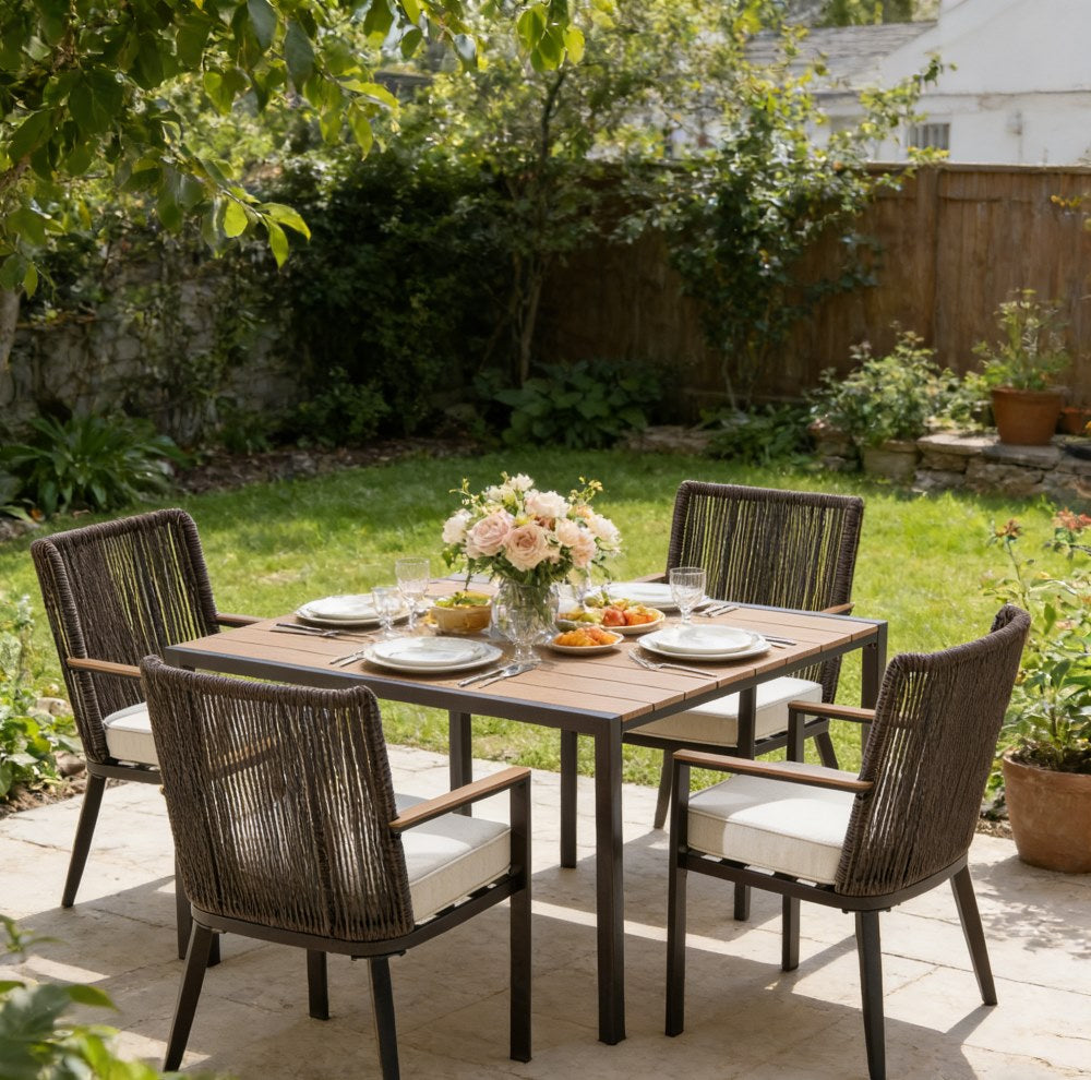 Outdoor dining setup with a table and chairs on a patio, surrounded by greenery.