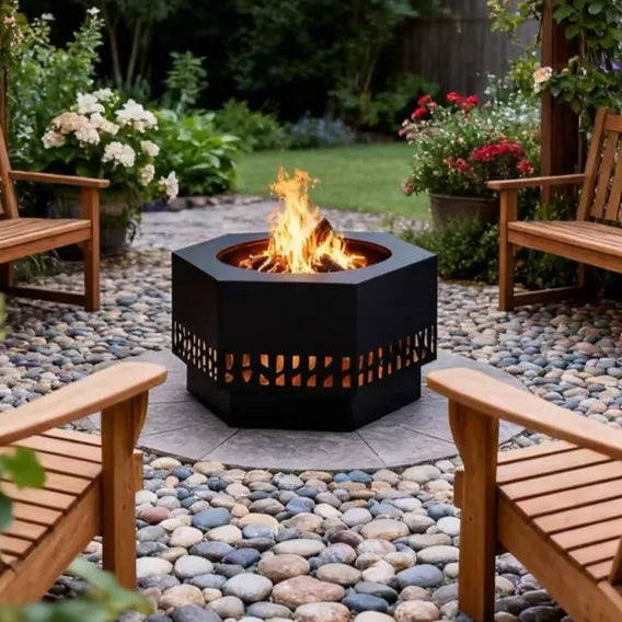 Hexagonal fire pit in a garden setting with wooden chairs and flowers.