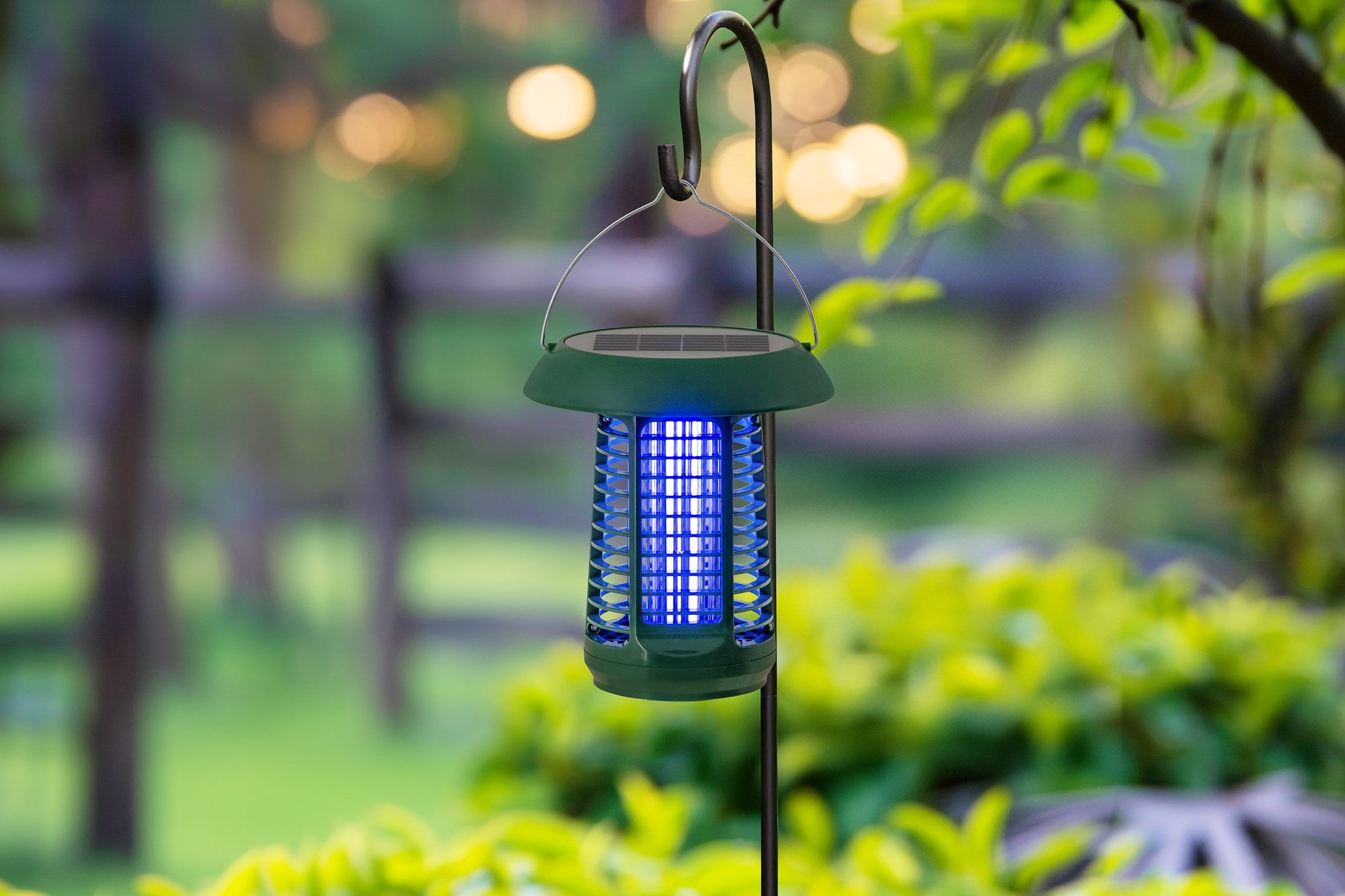 Solar mosquito zapper hanging outdoors with a blurred garden background