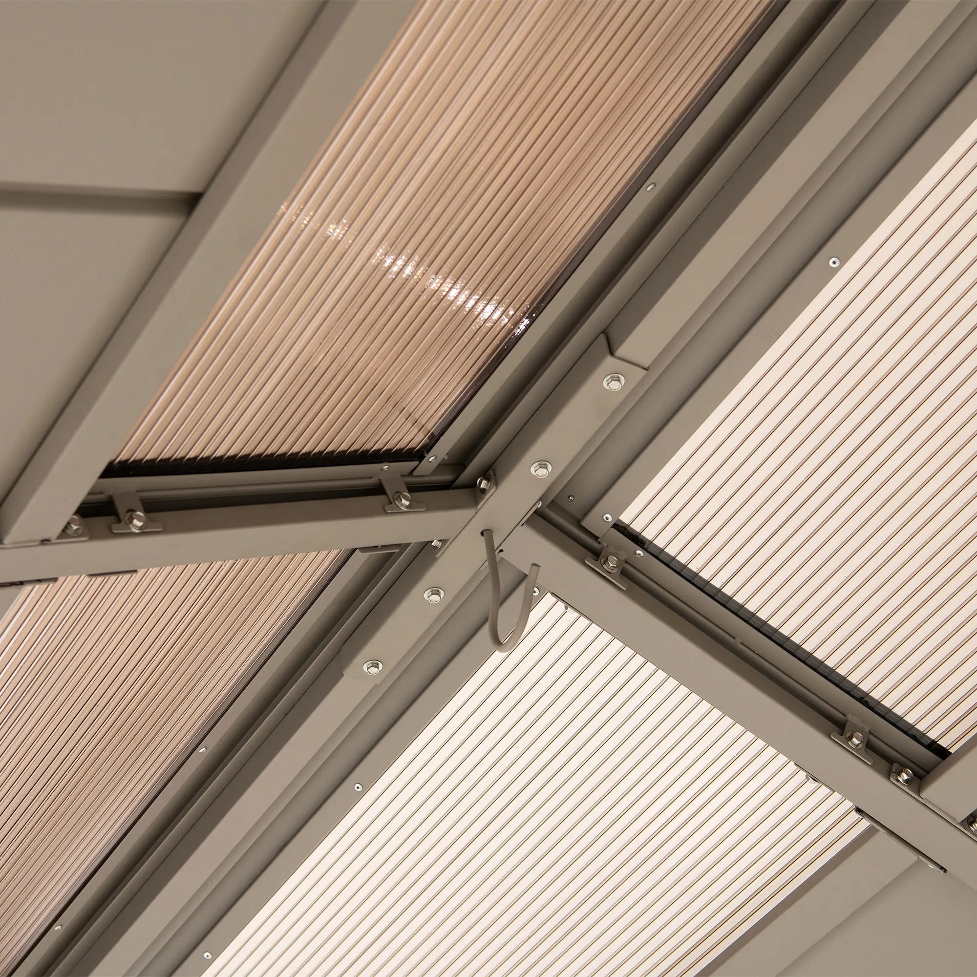 Close-up of a ceiling-mounted window shade or skylight panel with translucent slatted material and a gray metal frame.