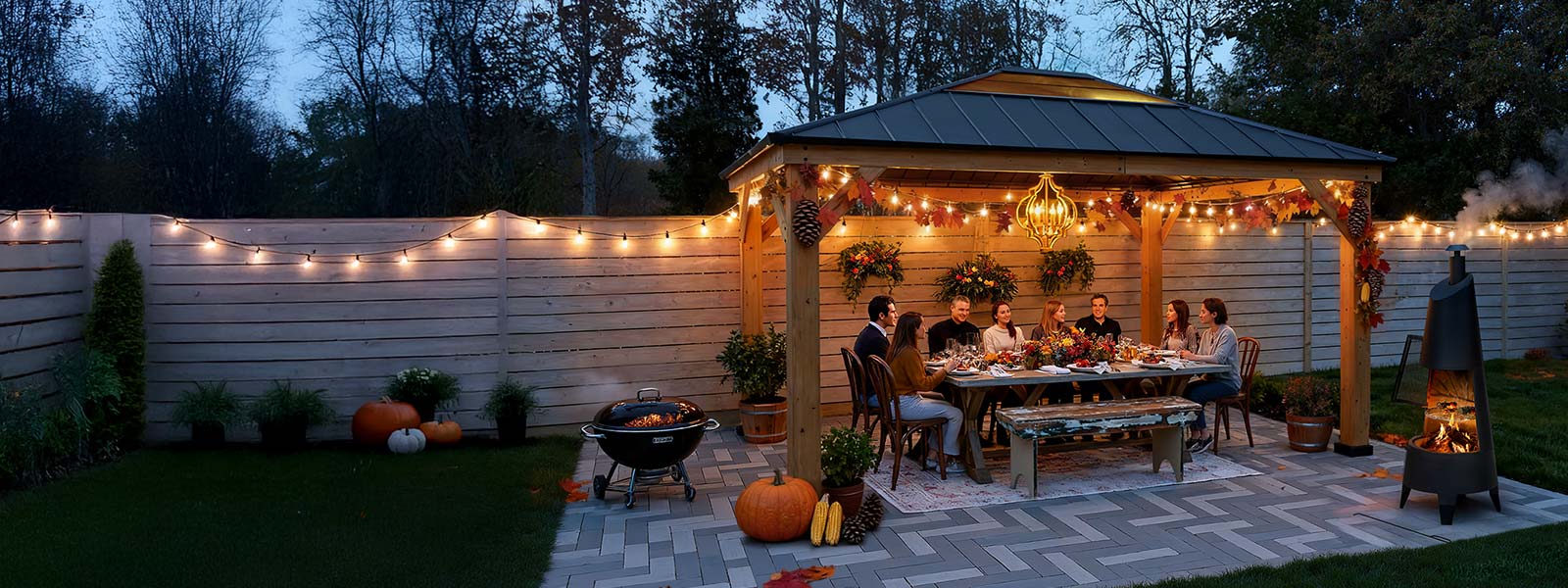 People enjoying a meal outdoors under string lights in a garden setting.