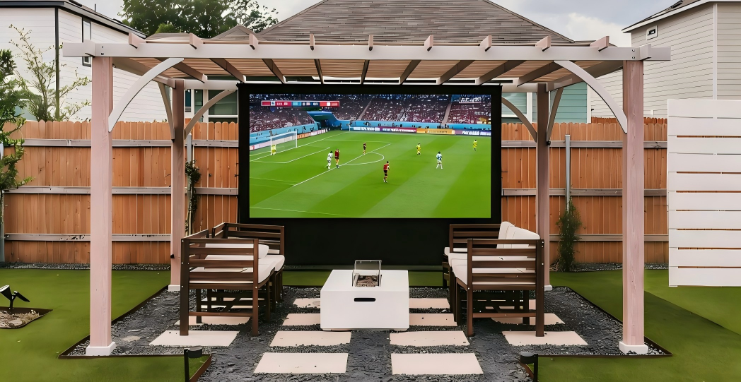 Outdoor setup with a screen displaying a sports event, chairs, and a fire pit.