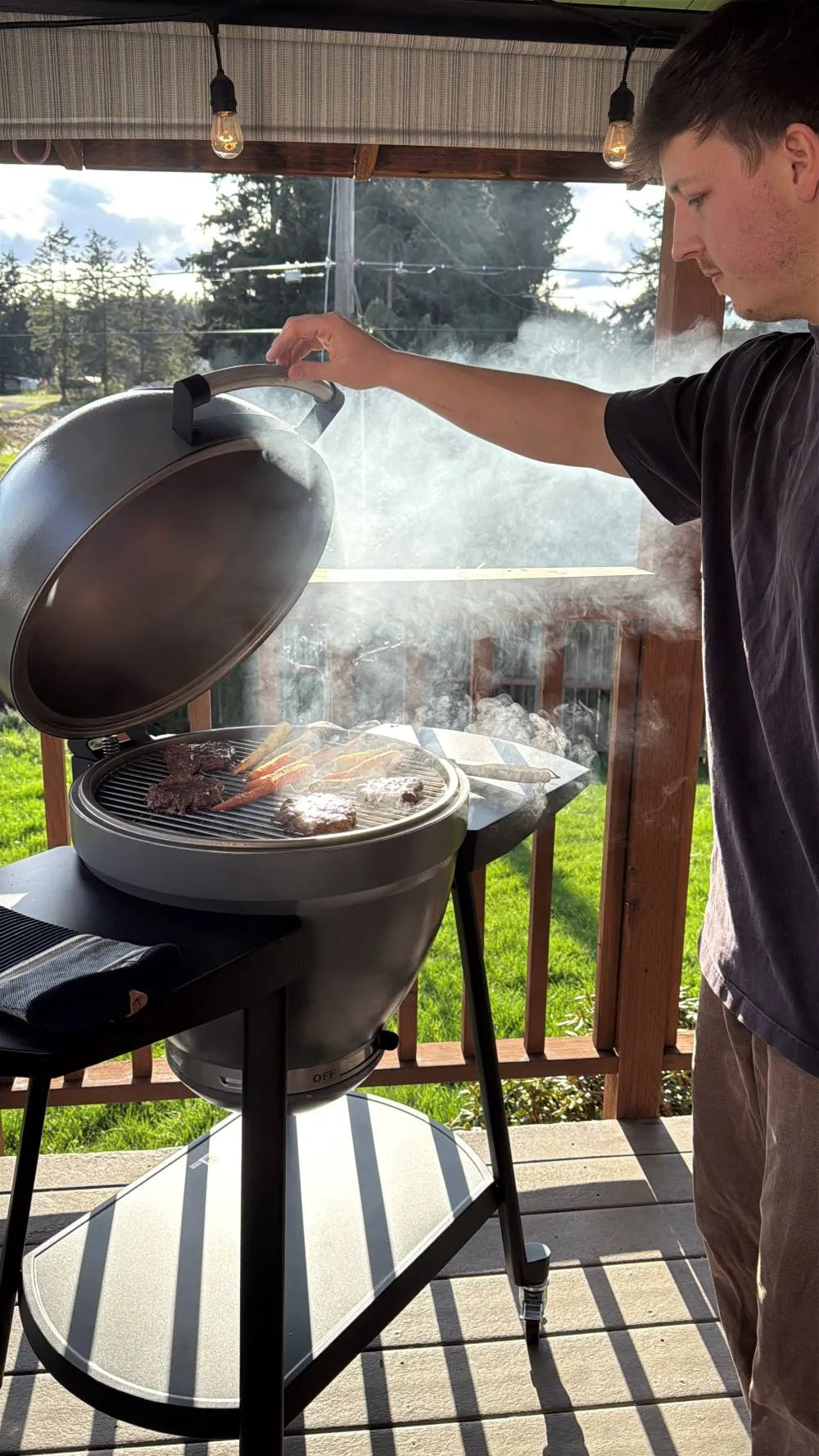 Person cooking outdoors on a grill with a covered dish