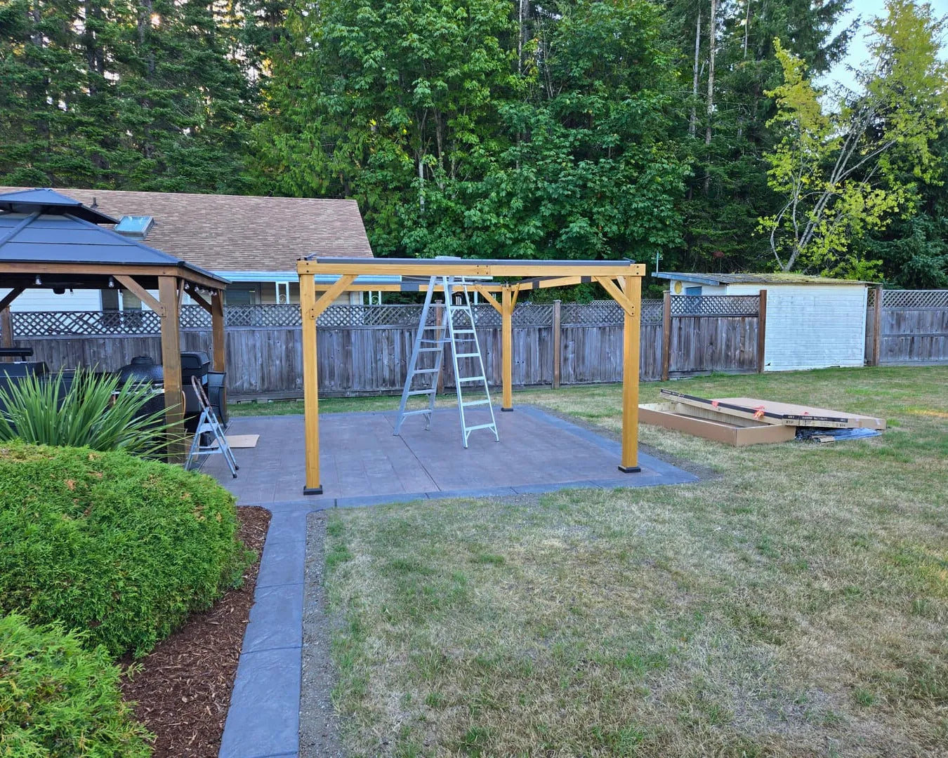 Backyard with wooden pergola structure, ladder, and outdoor furniture.